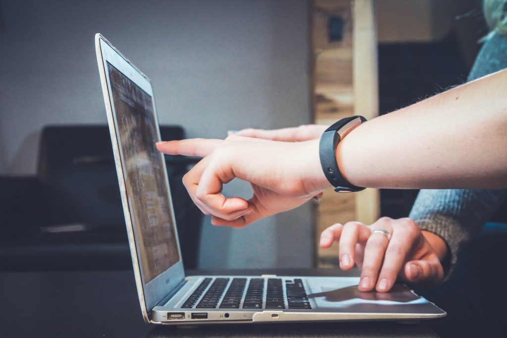 Two hands working on and pointing to screen of laptop computer