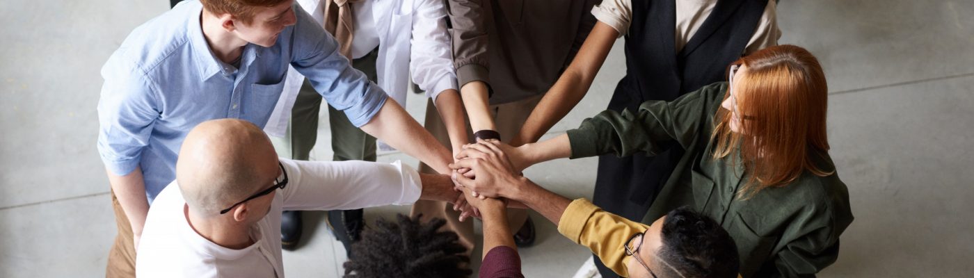 Group of people with hands meeting in the middle to signify teamwork.