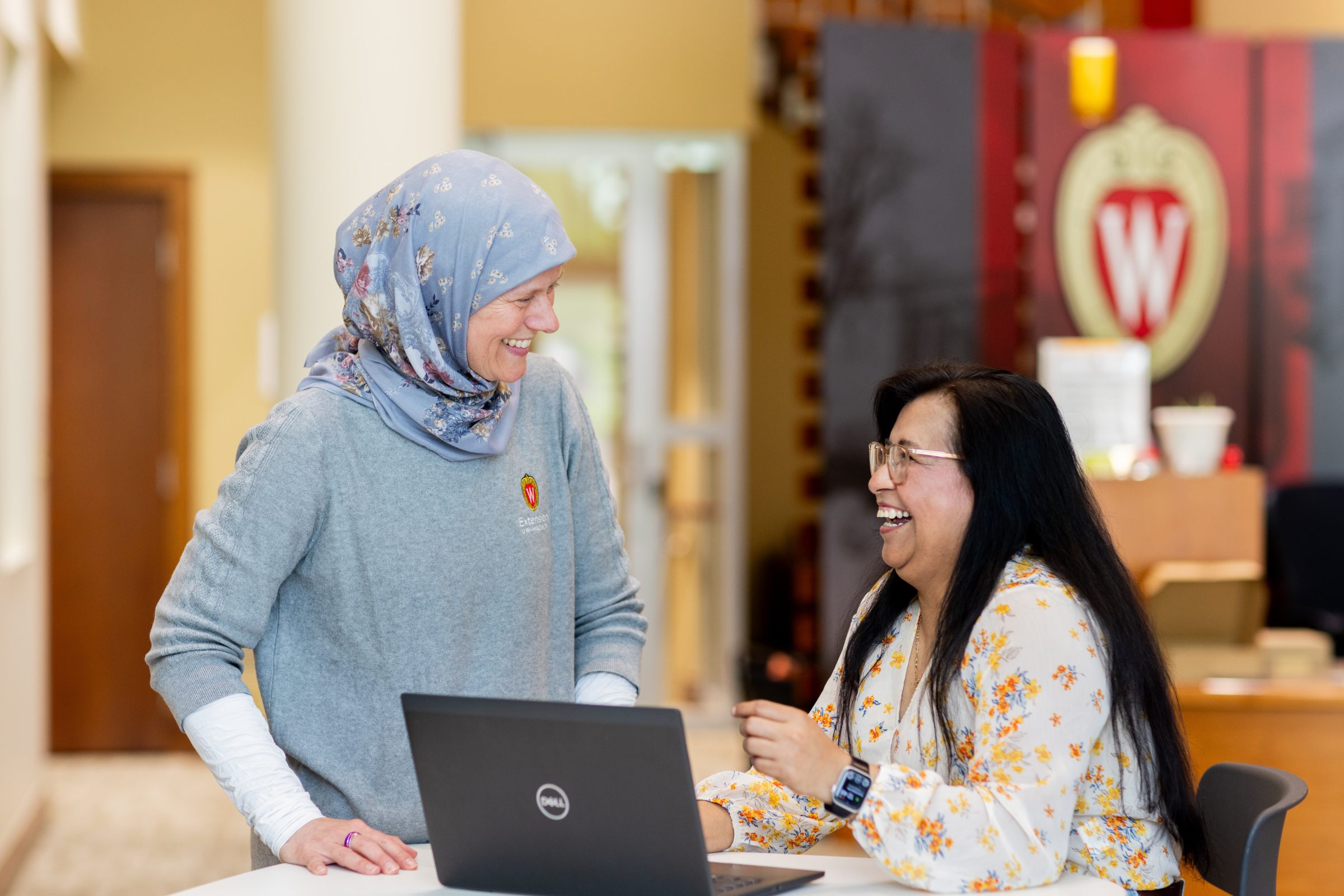 Two people gather to view a webinar on a laptop